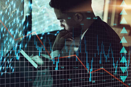 I dont think this is good. a young trader using his smartphone while monitoring the stock market.の写真素材