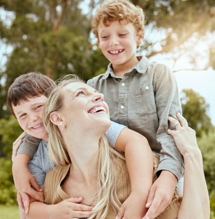 A happy caucasian single parent enjoying playing with her sons in the backyard. Smiling family of three having fun in a garden outsideの写真素材