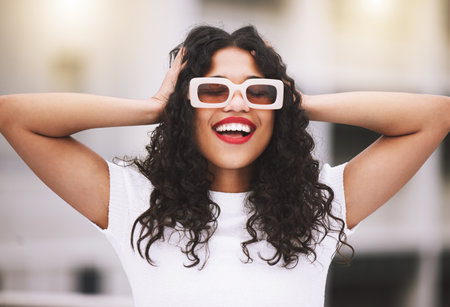 Beautiful mixed race fashion woman wearing sunglasses while standing outside. Young hispanic woman...