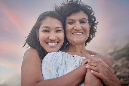 Portrait of a young hispanic woman spending the day at the beach with her elderly mother. Mixed race...
