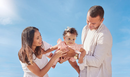 A happy mixed race family of three enjoying fresh air at the beach. Hispanic couple bonding with...