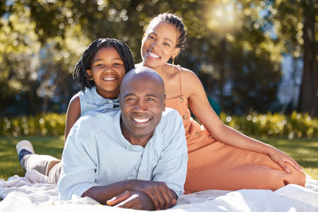 Portrait happy african american family of three spending quality time together in the park during...