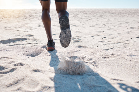 Feet of one black man running and jogging on sand at the beach in the morning for exercise. Closeup...