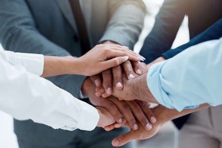 Teamwork is really a form of trust. a team of business people stacking their hands in motivation.