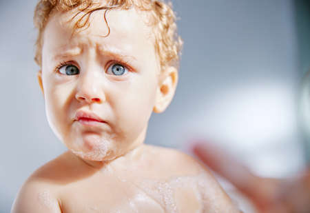 Can we just get bath time over with. an adorable baby boy taking a bath at home.の写真素材