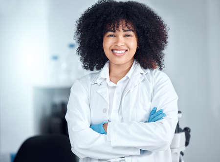 Portrait of a beautiful young african american woman with an afro wearing a labcoat and gloves while...