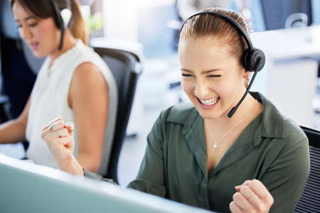 I just got the biggest client. an attractive young call centre agent sitting in the office and celebrating a success while using her computer.の写真素材
