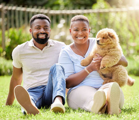 We all love hanging out at the park. Portrait of a young couple relaxing with their pet dog outdoors.の写真素材