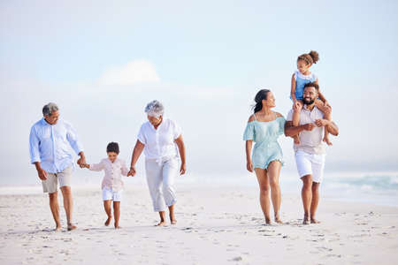 Multi generation family on vacation walking along the beach together. Mixed race family with two...