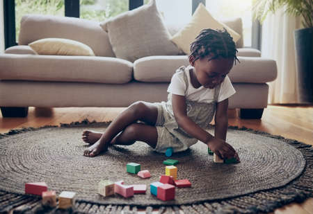 Laying a foundation. a little girl playing with blocks at home.の写真素材