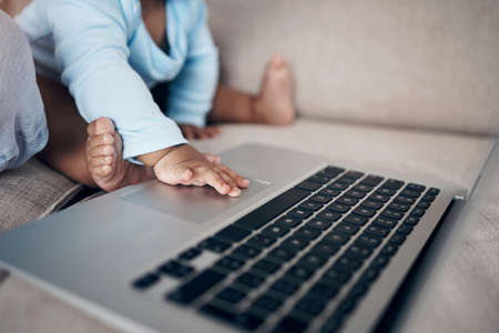 It works when mom does it. an unrecognizable woman using a laptop with her daughter on the sofa at home.の写真素材