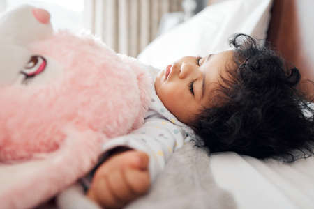 A better nap could not be taken. a baby girl sleeping in her bed.の写真素材