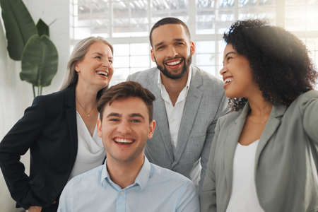 Group of four cheerful diverse and positive businesspeople taking a selfie together at work. Happy hispanic businesswoman taking a photo with her joyful colleaguesの写真素材