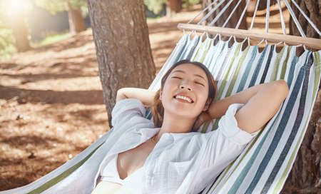 Now this is the life. an attractive young woman lying on a hammock during a day in the woods.の写真素材