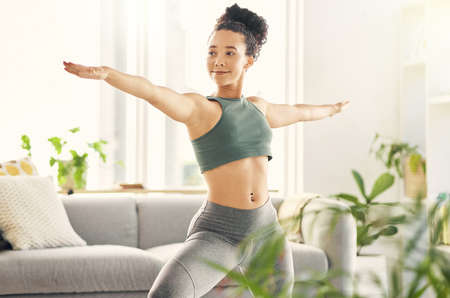 I dont worry too much because Im a warrior. a young woman practising yoga in her living room.