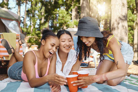 Its time to get the party started. a diverse group of friends bonding while camping in the woods.の写真素材