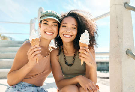This is what summer is all about. Cropped portrait of two attractive young girlfriends enjoying ice creams on the beach.の写真素材
