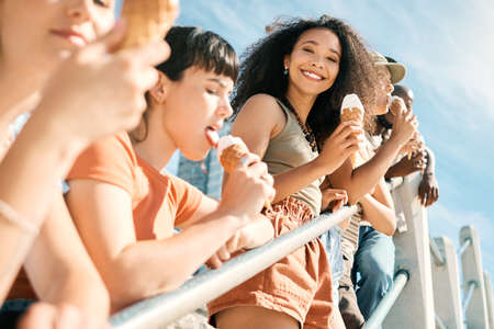 The best day ever. Cropped portrait of an attractive young woman enjoying an ice cream on the beach with her girlfriends.の写真素材