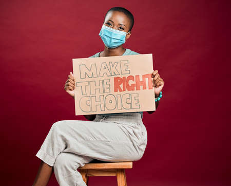 African american covid vaccinated woman showing, holding poster and wearing surgical face mask....