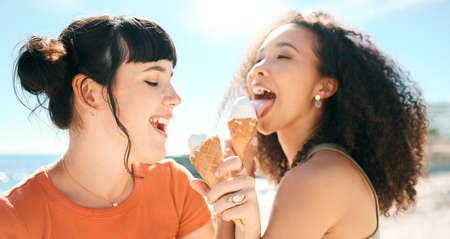 The season of sunshine and smiles. two attractive young girlfriends enjoying ice creams on the beach.の写真素材