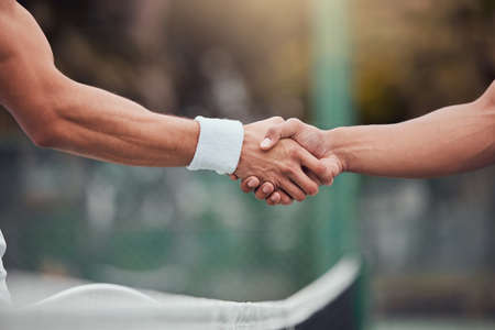 Two unknown ethnic tennis players shaking hands before playing court game. Fit athletes team standing and using hand gesture handshake for good luck. Play competitive sports match for health fitnessの写真素材