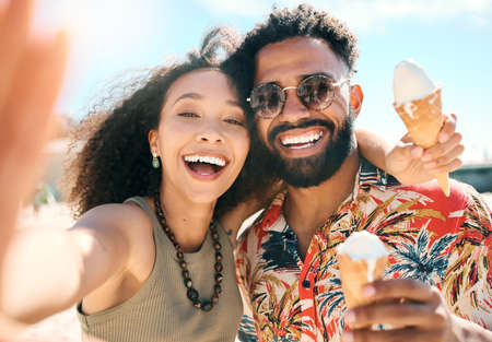Ice cream dates. Cropped portrait of an affectionate young couple taking selfies while enjoying ice creams on the beach.の写真素材