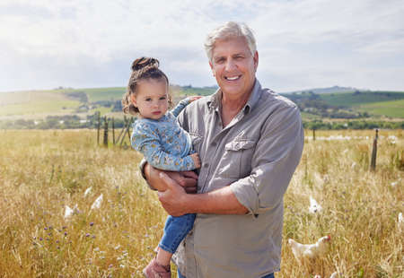 She loves visiting my farm. a mature man bonding with his granddaughter on a poultry farm.の写真素材