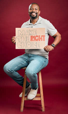 African american covid vaccinated man showing and holding poster. Smiling black man isolated against red studio background with copyspace. Happy model using sign to promote corona vaccine and motivateの写真素材
