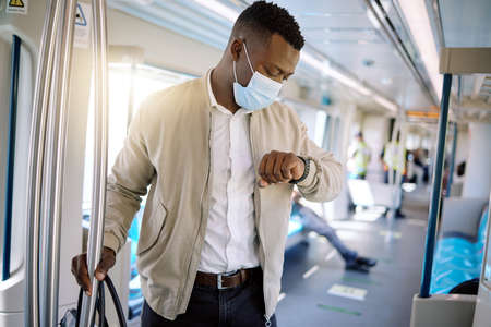 Black businessman travelling alone. A young african american businessman standing on a train while...