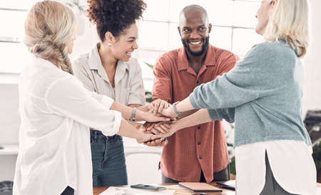 Group of diverse businesspeople piling their hands together in an office at work. Business...