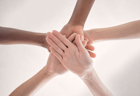 Group of diverse businesspeople piling their hands together in an office at work. Business...