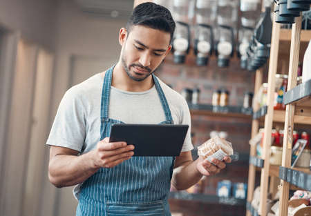 one young hispanic waiter using a digital tablet device while working in a store or cafe. Mixed race...