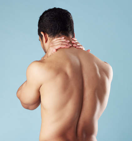 Rearview young mixed race man standing shirtless in studio isolated against a blue background....