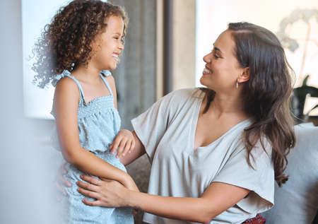 Adorable little girl and loving mother talking and laughing while spending time together at home....