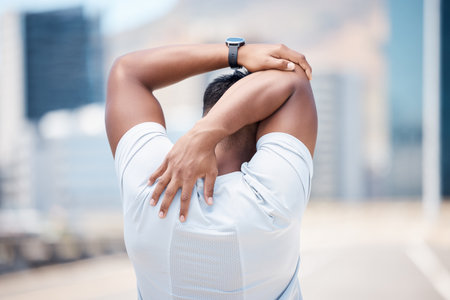 Rear view of a fit young mixed race man stretching his arms behind his head before his run outdoors...