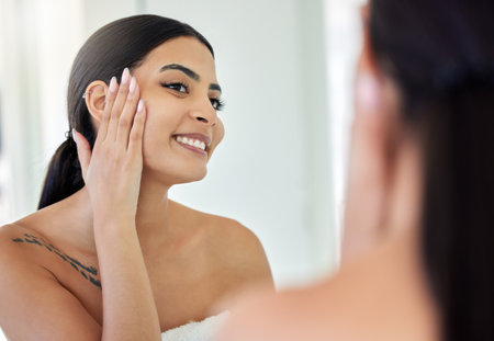 The glows back. a young woman doing her skincare routine in a bathroom at home.の写真素材