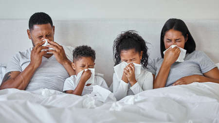 Flu season. a family blowing their noses while sick at home.の写真素材