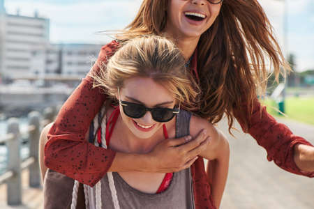 Ill carry you through this life. a woman giving her friend a piggy back ride.の写真素材