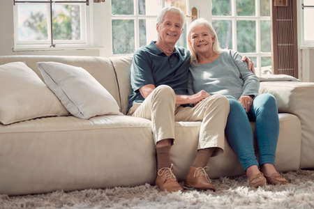 I knew she was the one from the beginning. Full length portrait of an affectionate senior couple sitting in their living room at home.の写真素材