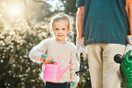 The most beautiful little flower in my garden. an adorable little girl gardening with her grandfather.の写真素材