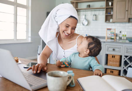 Mommas got bills to pay. a mom working on her laptop with her baby on her lap.の写真素材