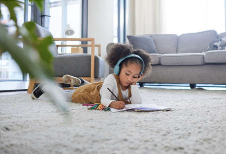 Letting her express herself. a little girl drawing while listening to music at a psychologists office.の写真素材