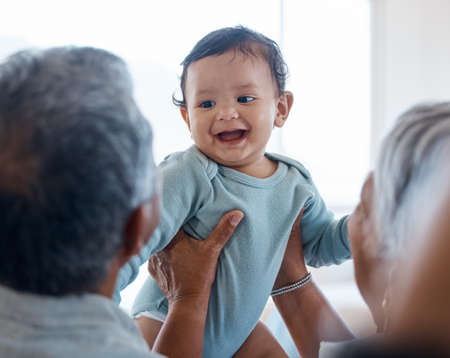 Hanging onto baby breath. grandparents bonding with their grandchild on a sofa at home.の写真素材