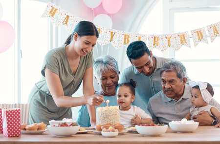 Blow, baby. a family celebrating a birthday together at home.