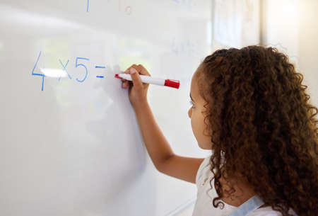 This is like my home away from home. a little girl doing maths on a board in a classroom.