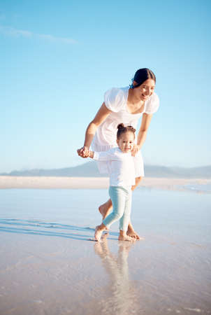 Beach days are fun and keeps you active. a young woman at the beach with her adorable daughter.の写真素材