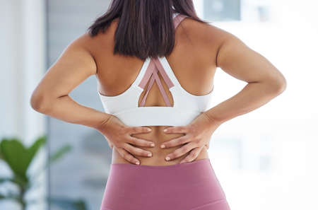 Be careful or youll break your back. Rearview shot of a sporty young woman pressing her back in a yoga studio.の写真素材