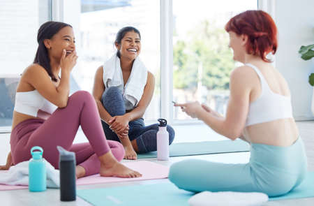 They joined as a hobby and made friends along the way. a group of sporty young women taking a break while exercising in a yoga studio.の写真素材