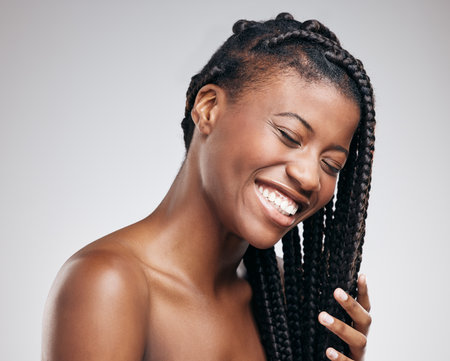 Her skin is as firm as her braids. an attractive young woman posing in studio against a brown background.の写真素材