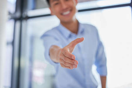 Closeup of one business man extending hand forward to greet and welcome with handshake. Networking...
